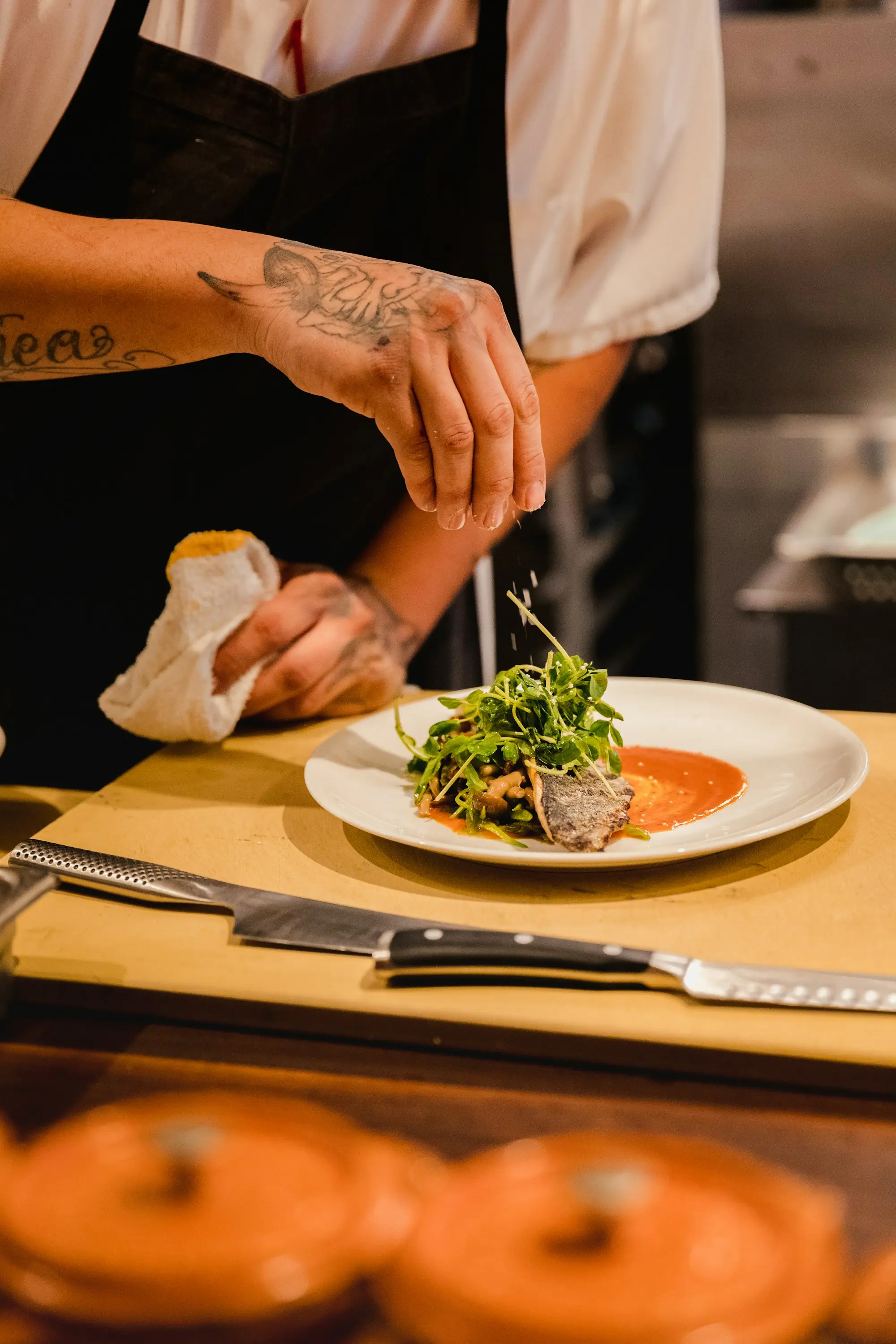 Chef in whites plating a finished dish in a professional kitchen