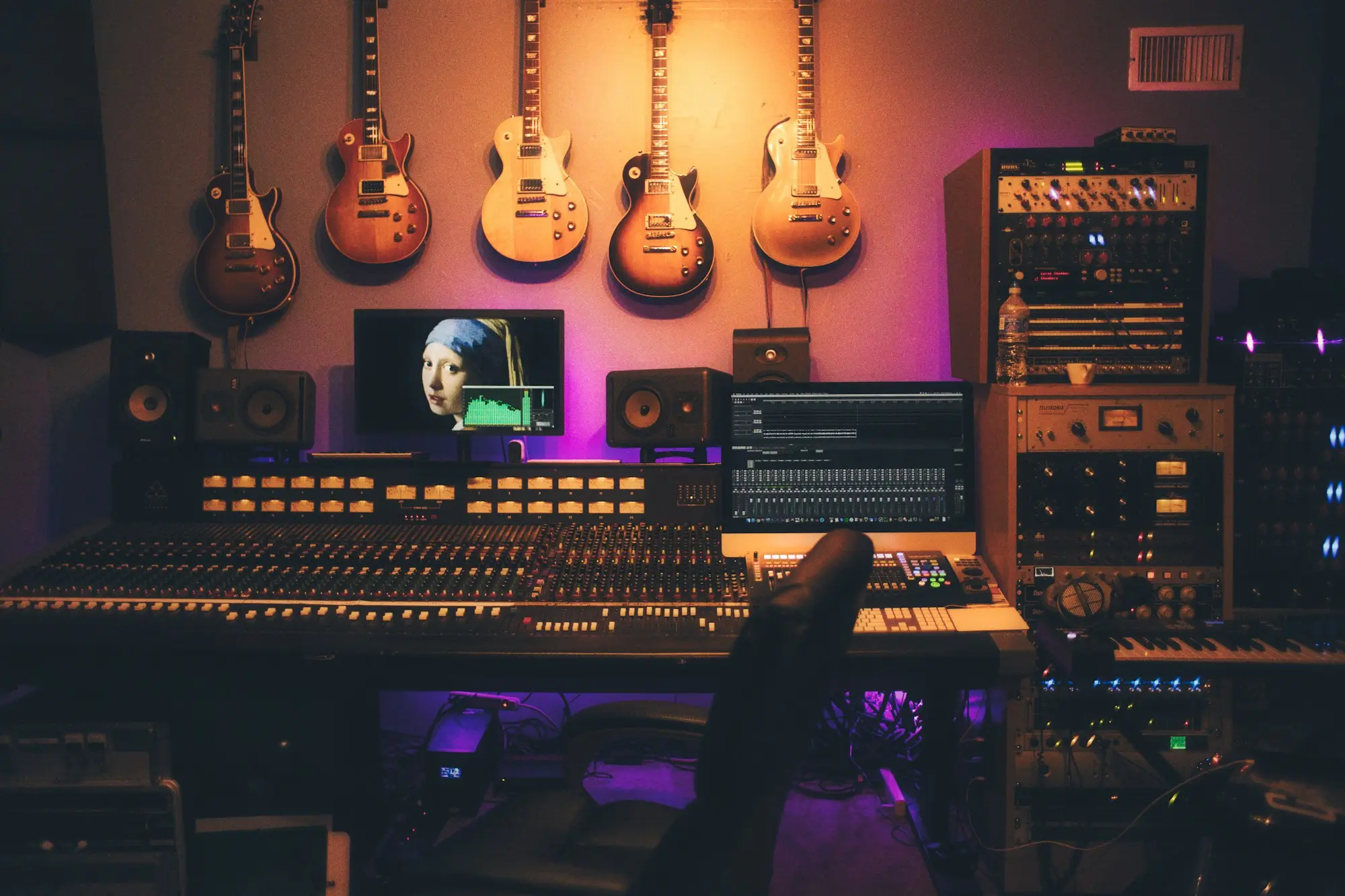 Producer in front of guitars and a mixing console at night