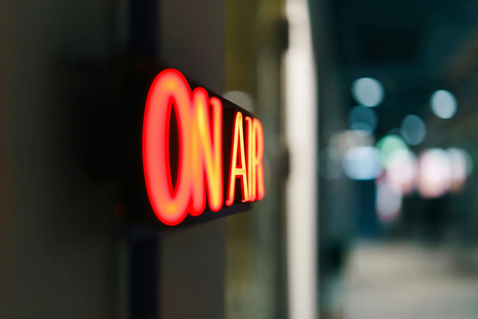 Red ON AIR neon sign glowing in a darkened broadcast studio